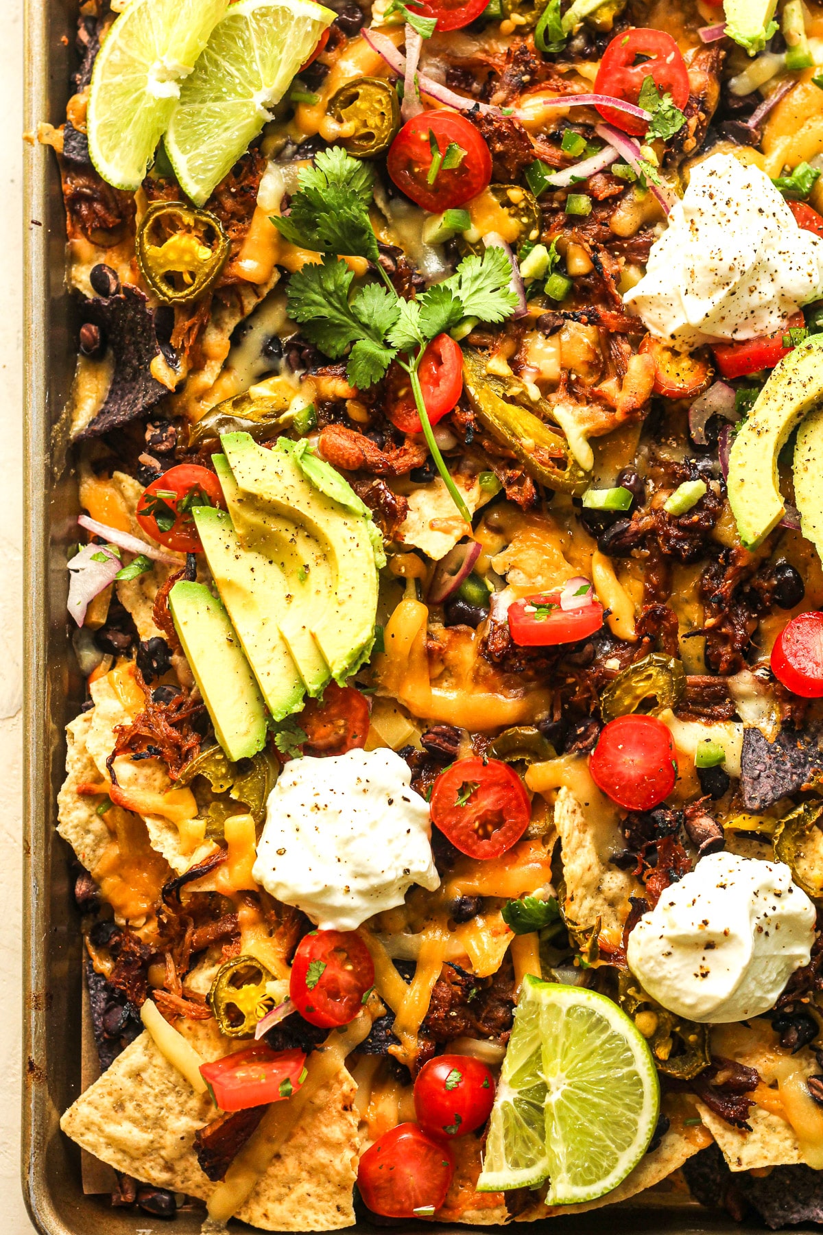 Another view of a sheet pan of nachos with toppings.