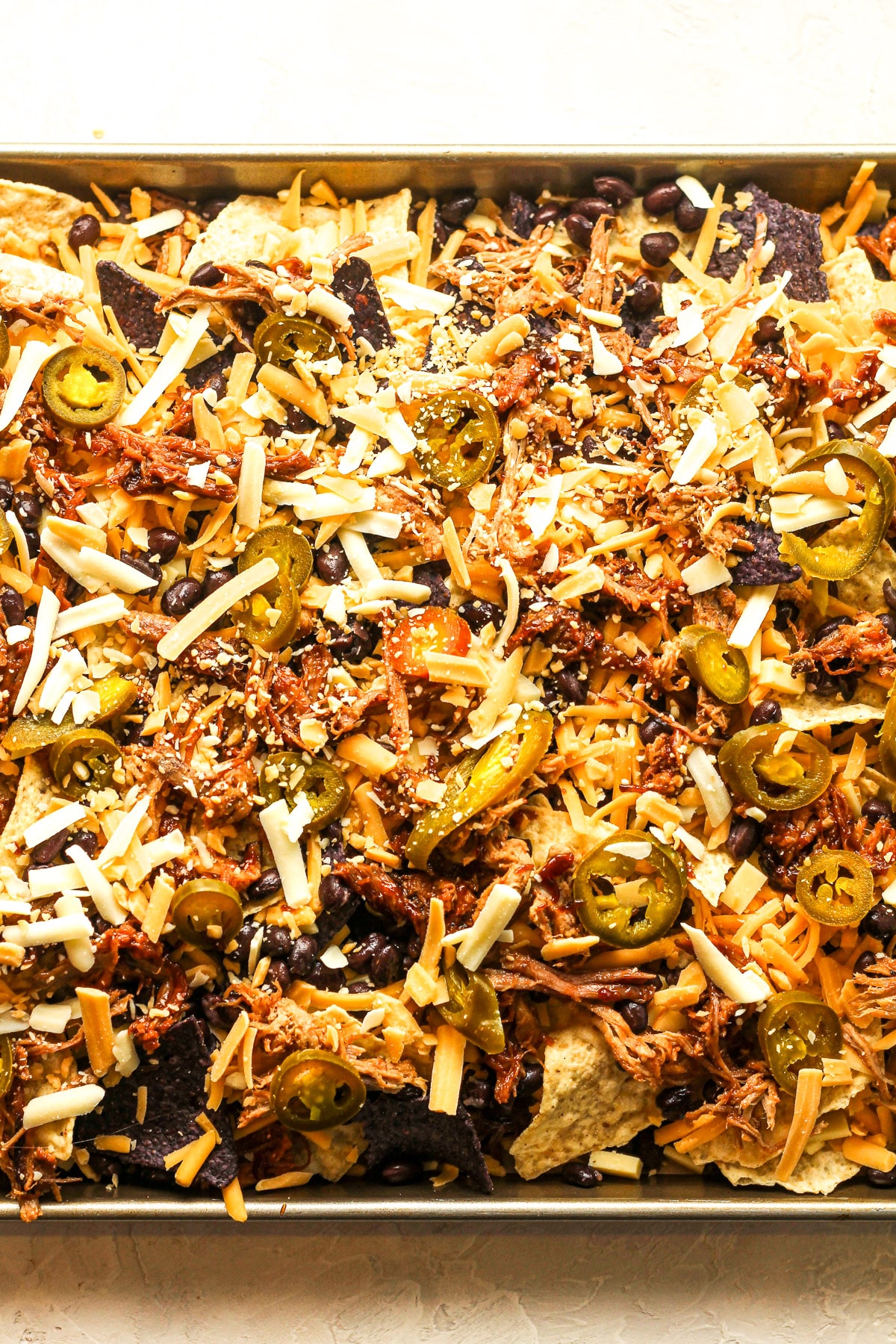 Overhead view of a tray of prepped nachos before baking.