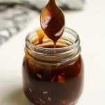 A spoon dripping homemade teriyaki sauce in a small mason jar.