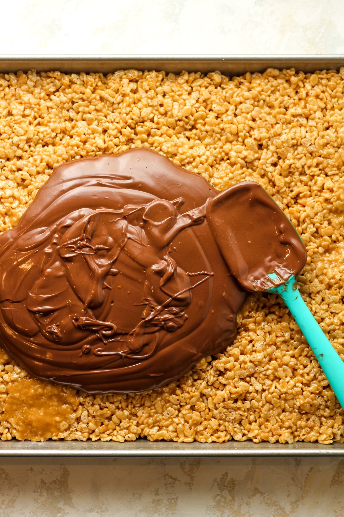 A pan of the Rice Krispie layer with the topping poured out on top before sppreading out.
