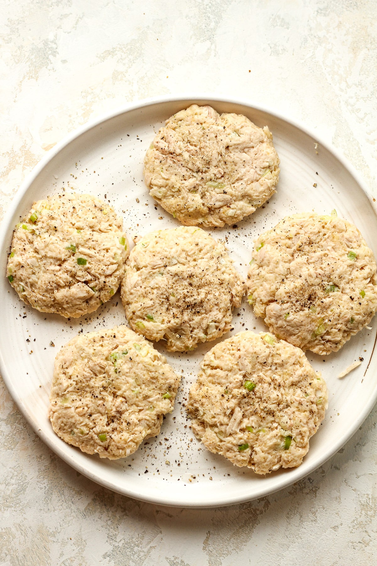 A plate of six tuna patties before browning.