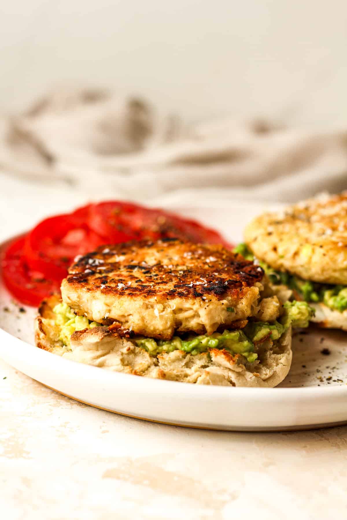A plate of two tuna patties on English muffin halves with avocado.