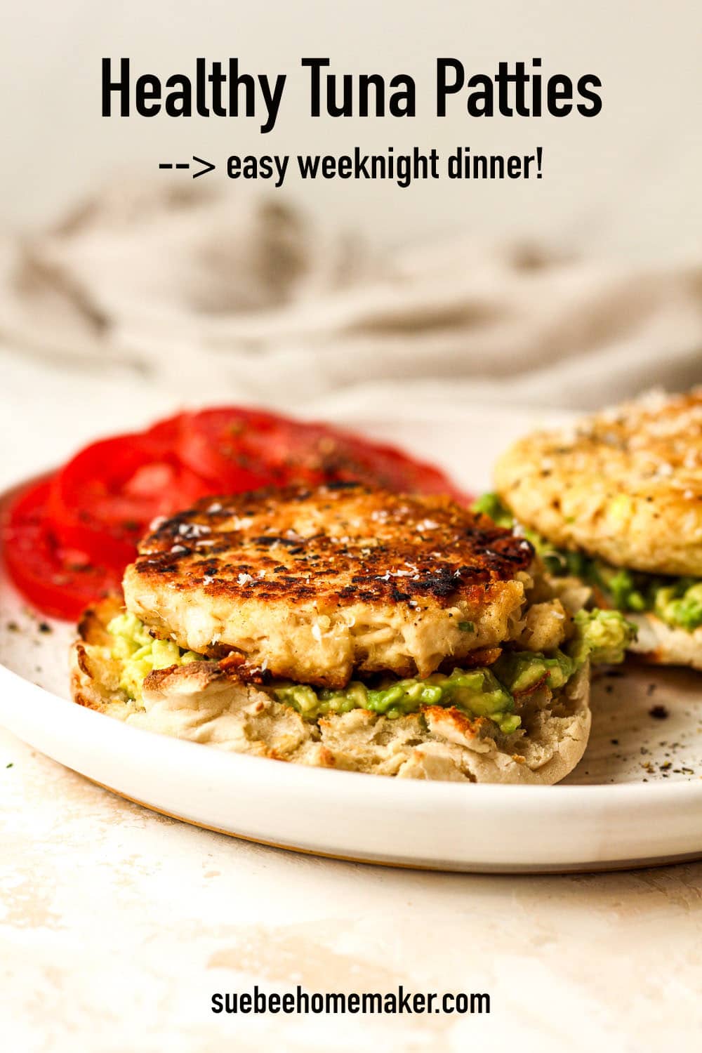 Side view of healthy tuna patties on English muffins with avocado and tomato.