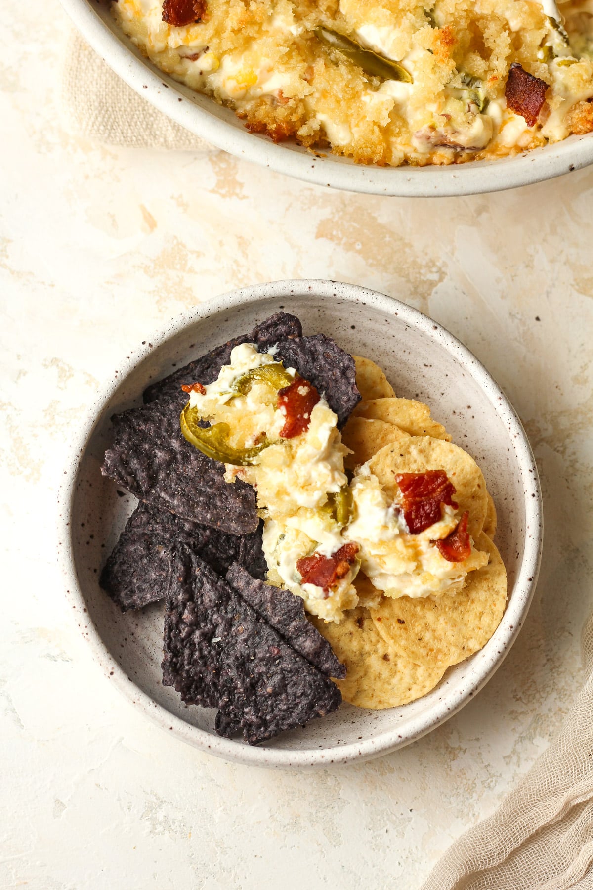 A small bowl of chips topped with jalapeño popper dip.