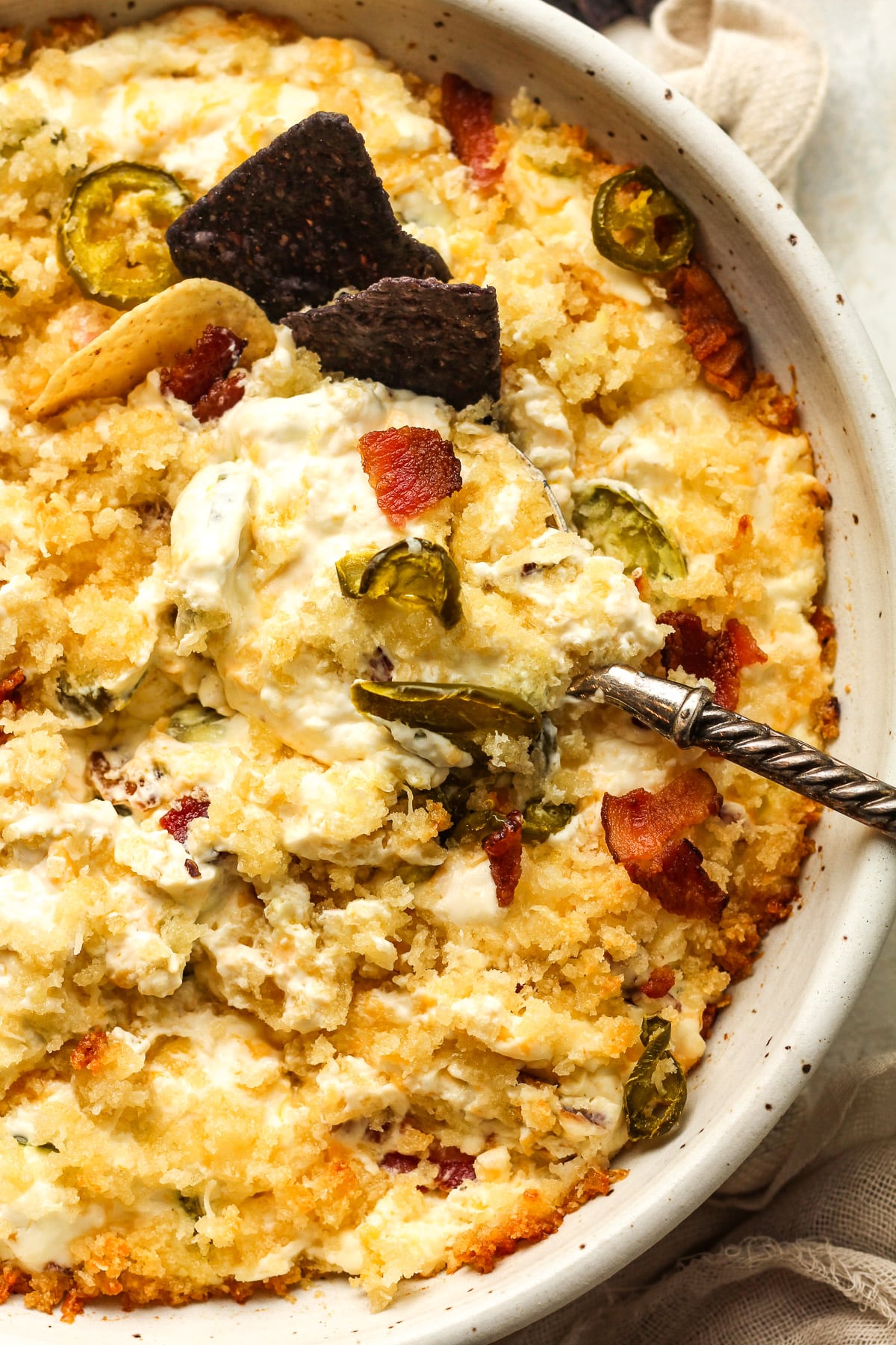 Closeup on a bowl of jalapeño popper dip with a spoon.