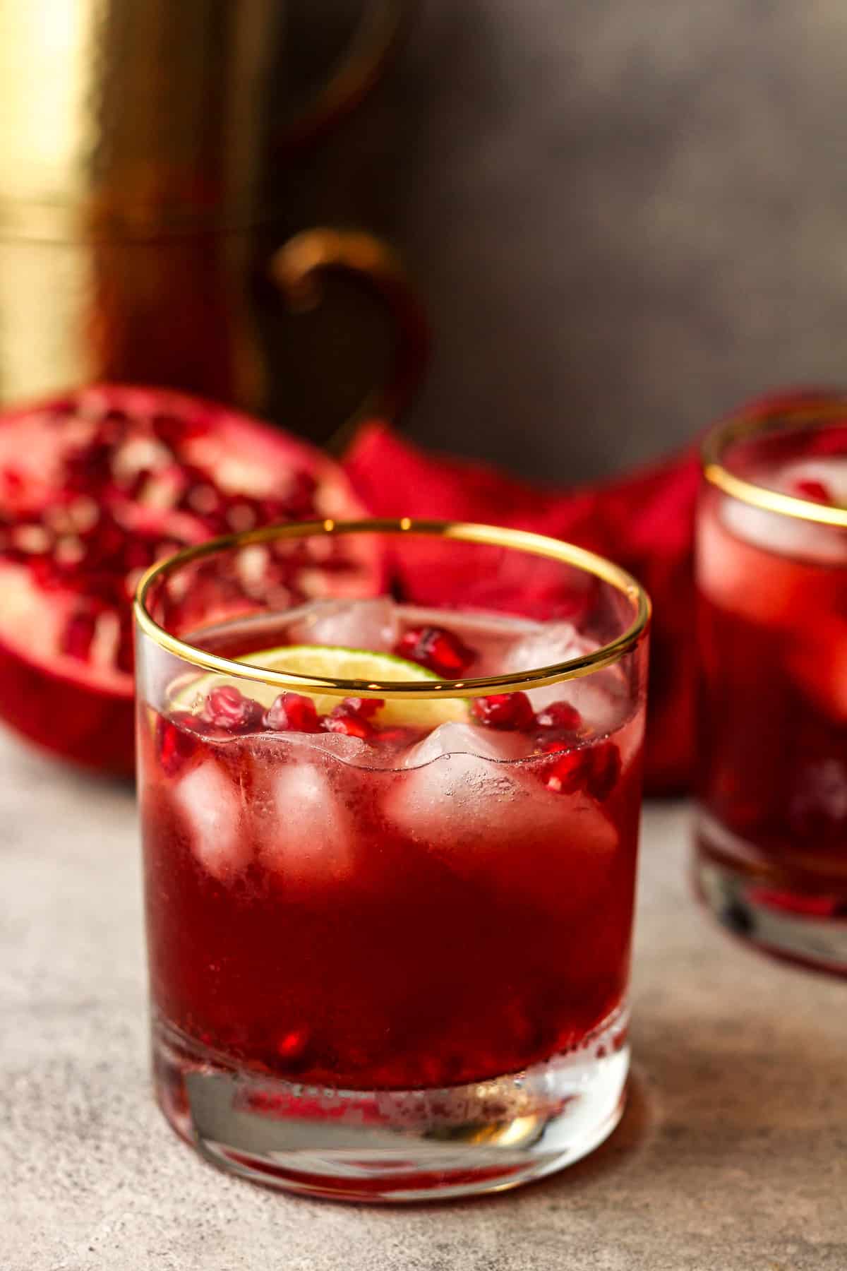 Side view of two gold-rimmed glasses of pomegranate Moscow mules.