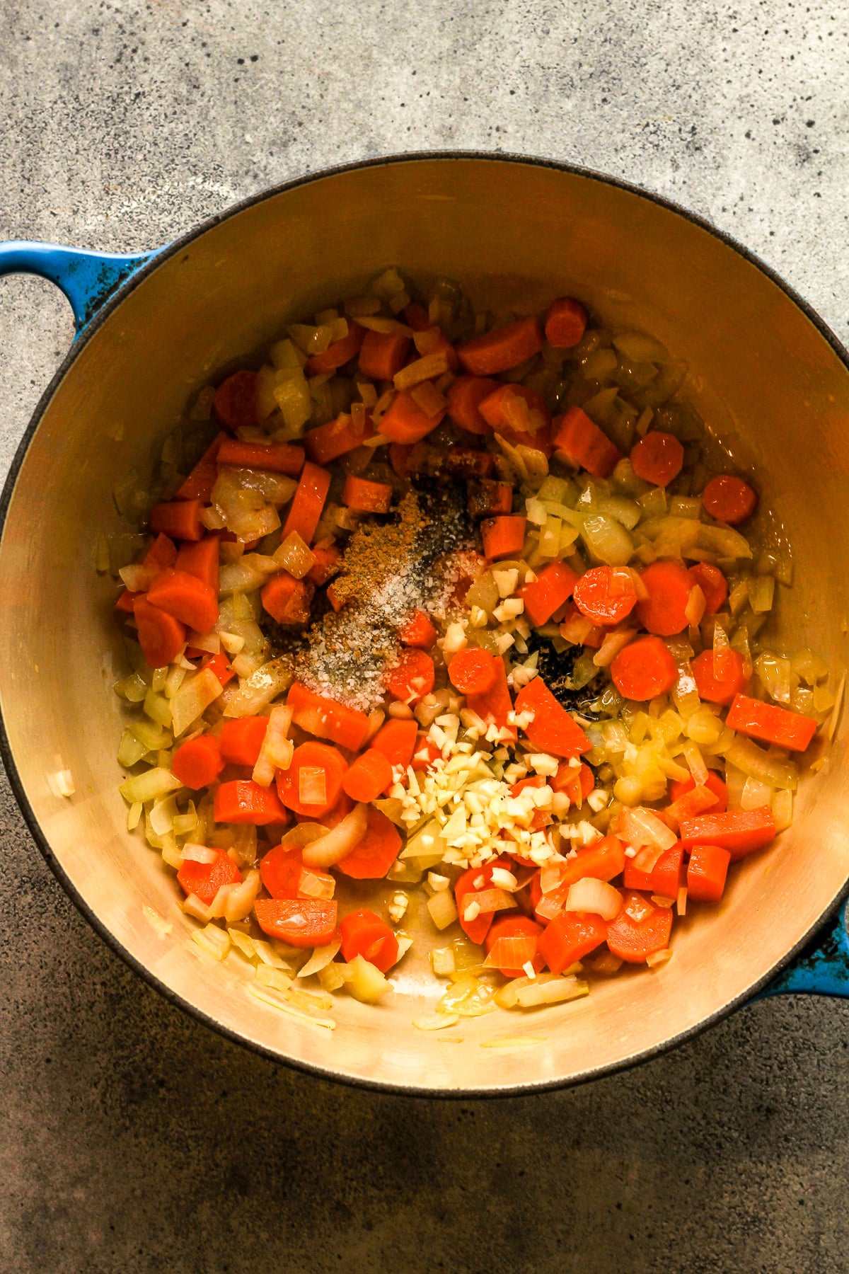 The pot with the sauteed onion and carrots with the seasonings and garlic on top.