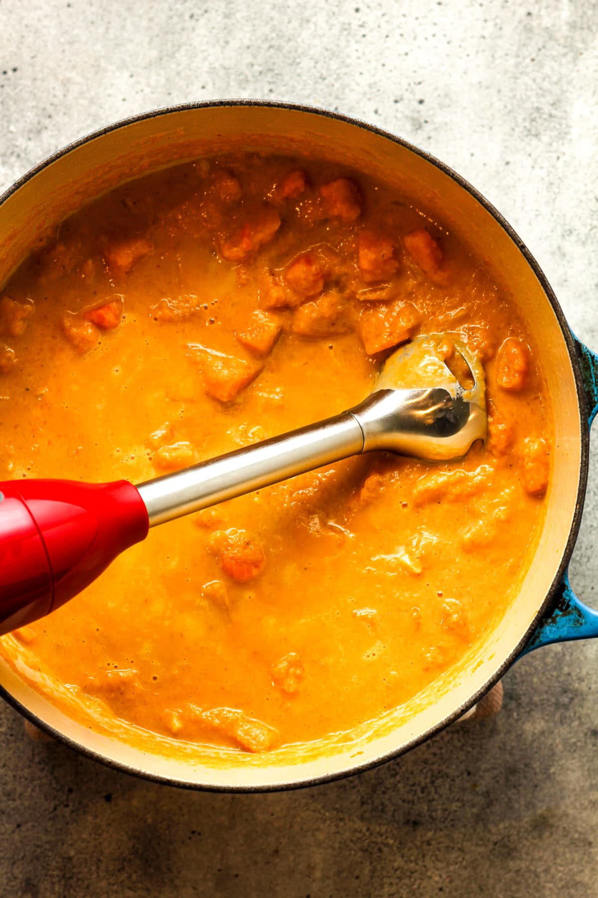 The immersion blender in the pot before blending.