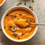 Closeup on a bowl of Autumn squash soup with a spoonful on top.