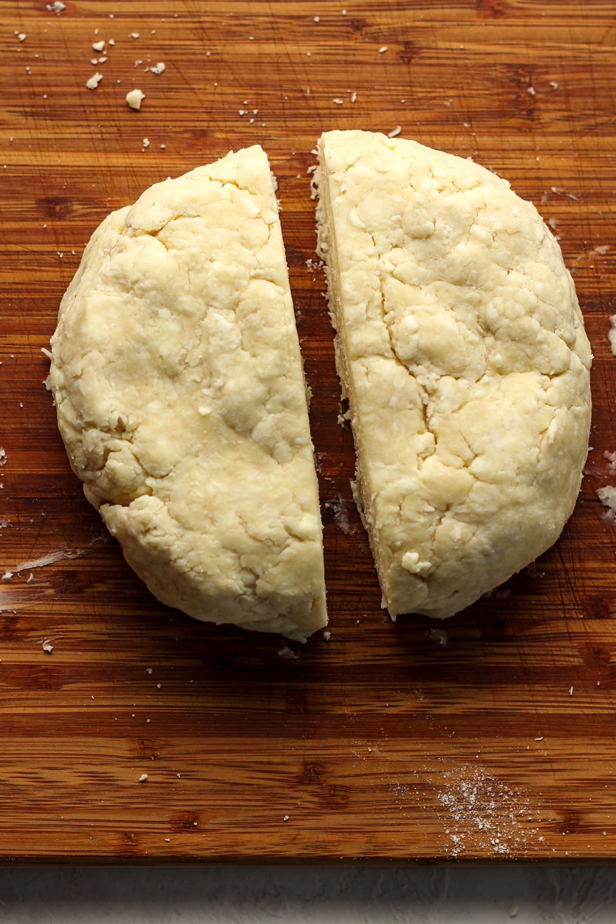 The round of pie dough cut in half on a board.