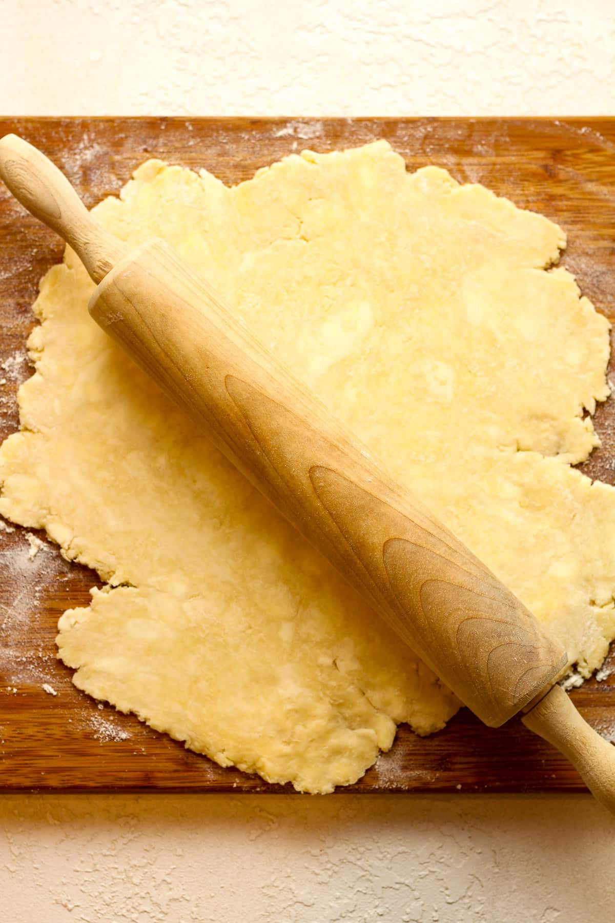 The pie dough rolled out on a floured cutting board.
