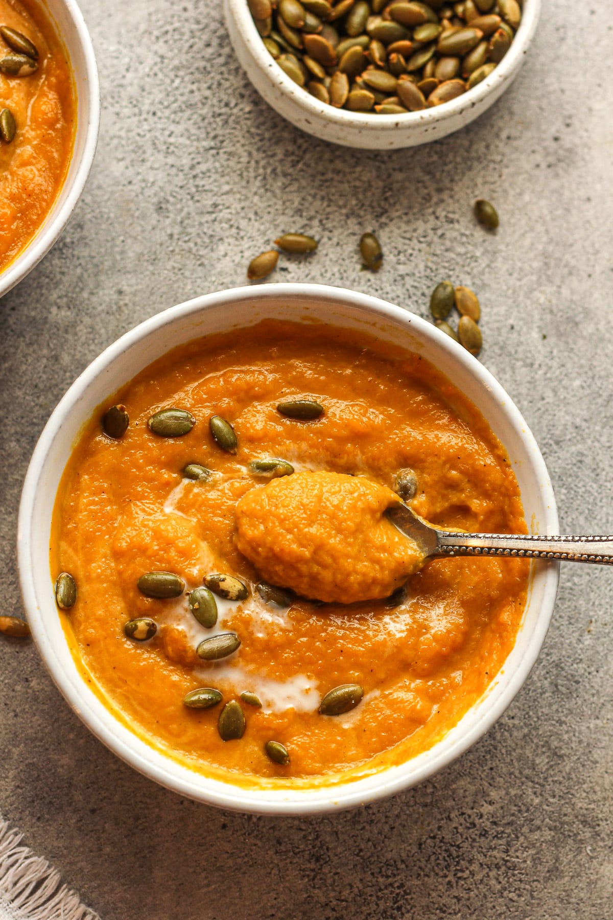 Overhead view of a bowl of Autumn squash soup with a spoonful on top.