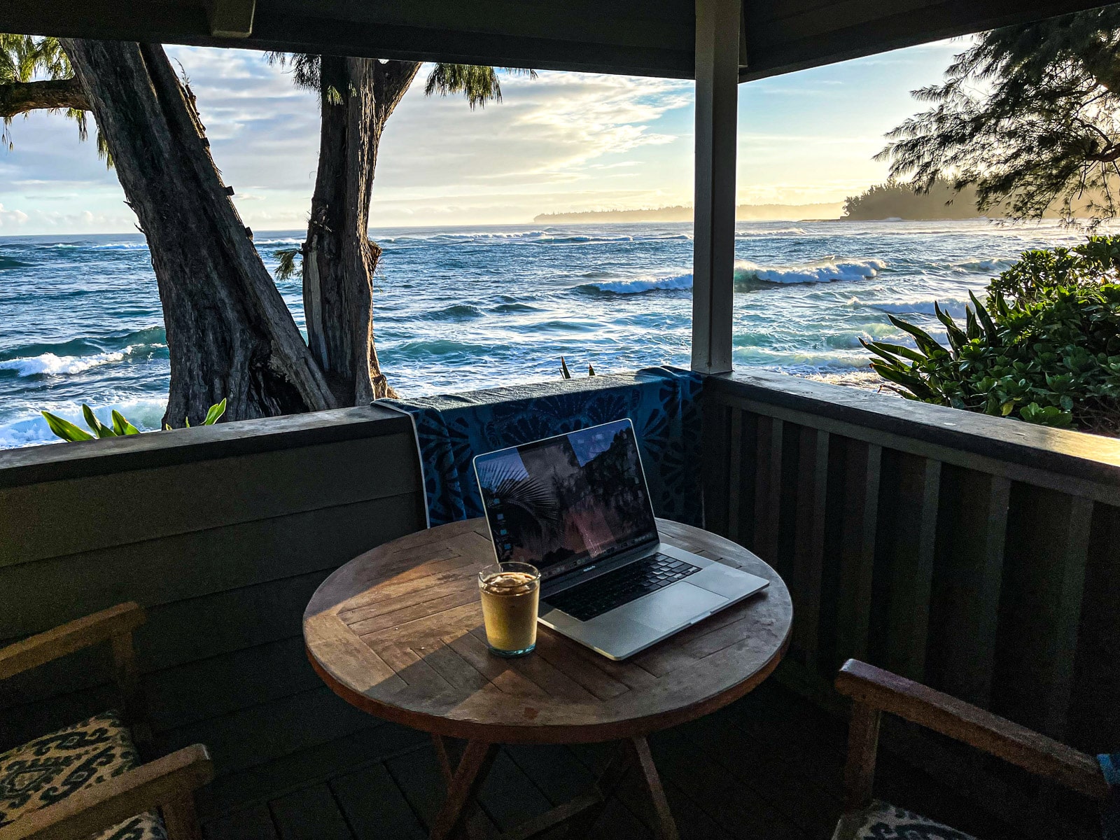 My computer and iced coffee in the morning by the ocean.