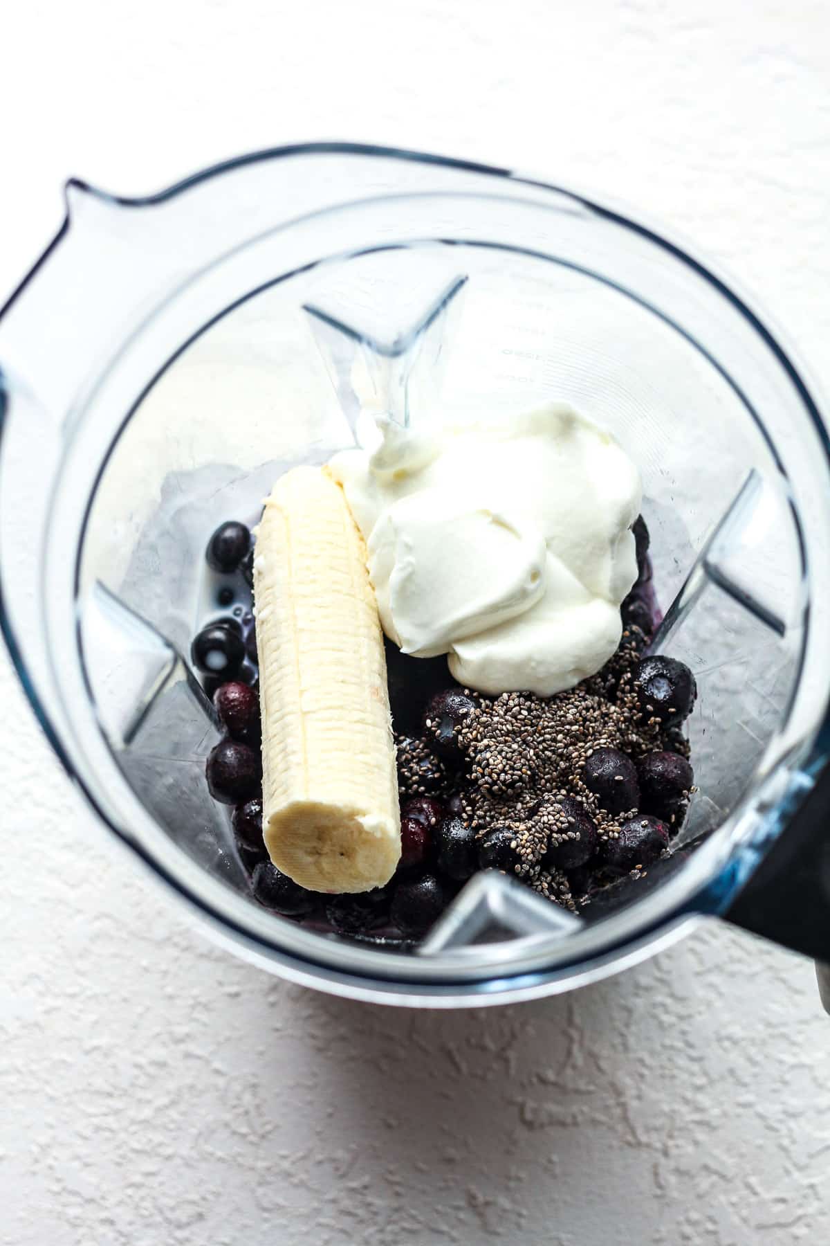 Overhead view of a blender with the blueberry smoothie ingredients.