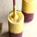Side view of two blueberry mango smoothies with glass straws.