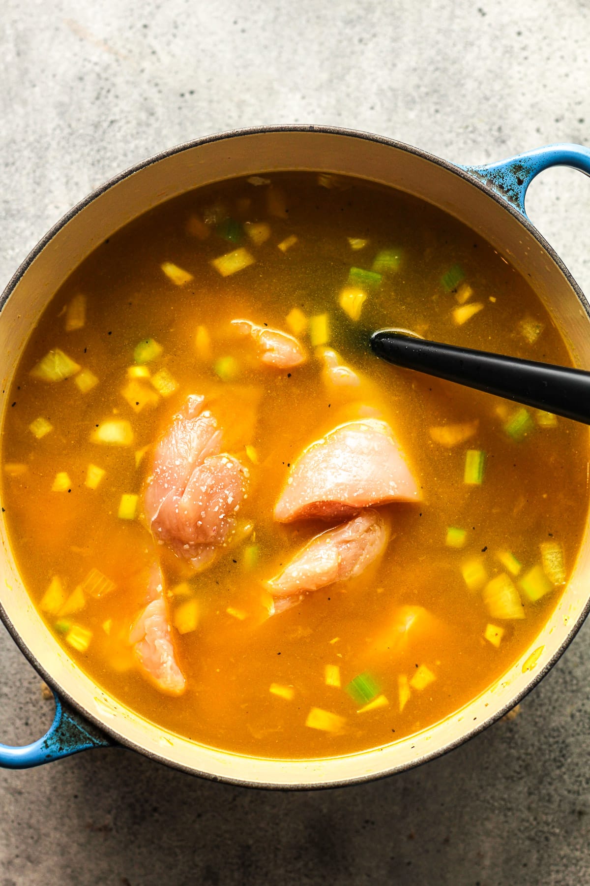 A pot of the soup after adding in the raw chicken chunks.