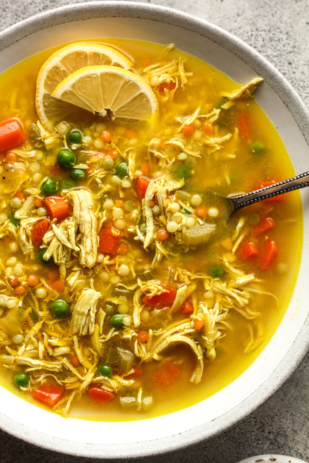 Overhead shot of a bowl of chicken and couscous soup with turmeric.