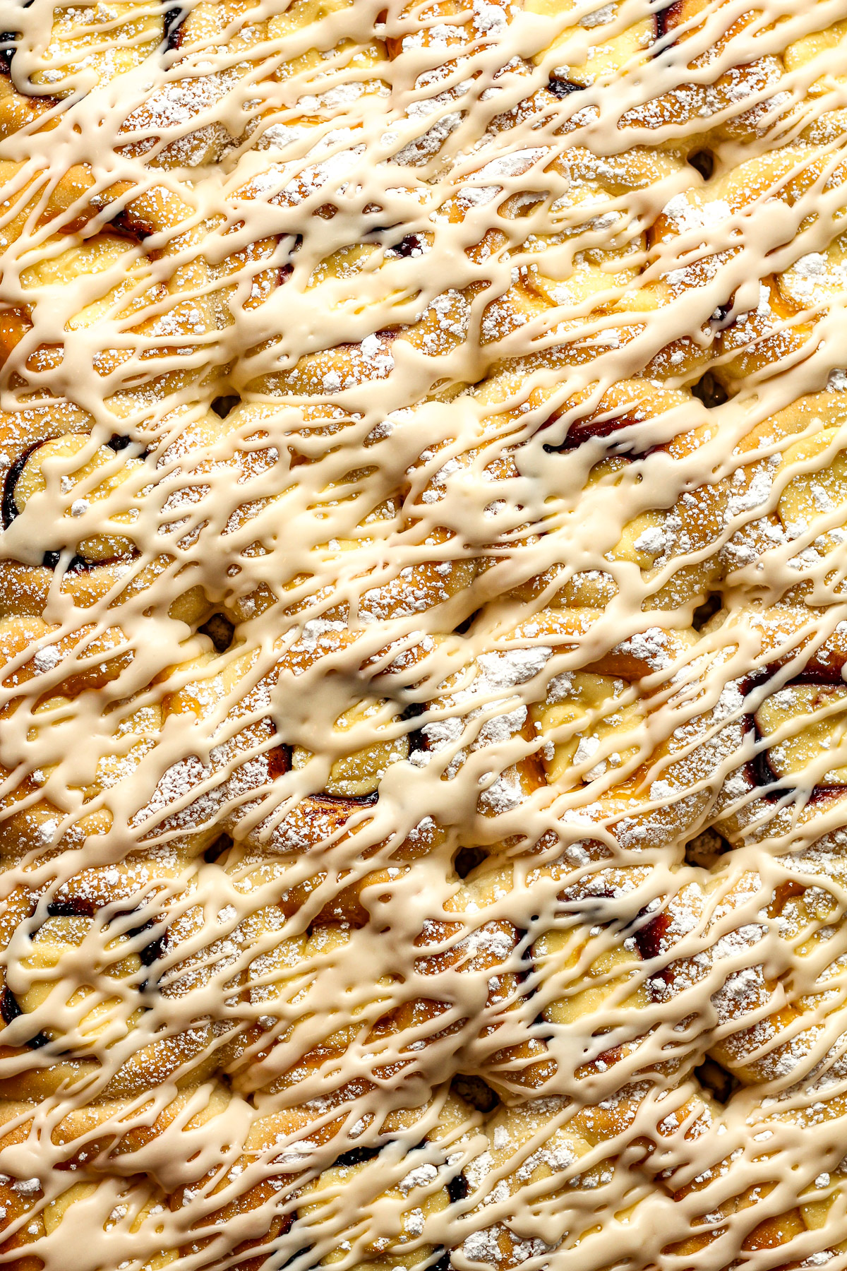 A large pan of cream cheese kolaches with fruit and a simple icing.