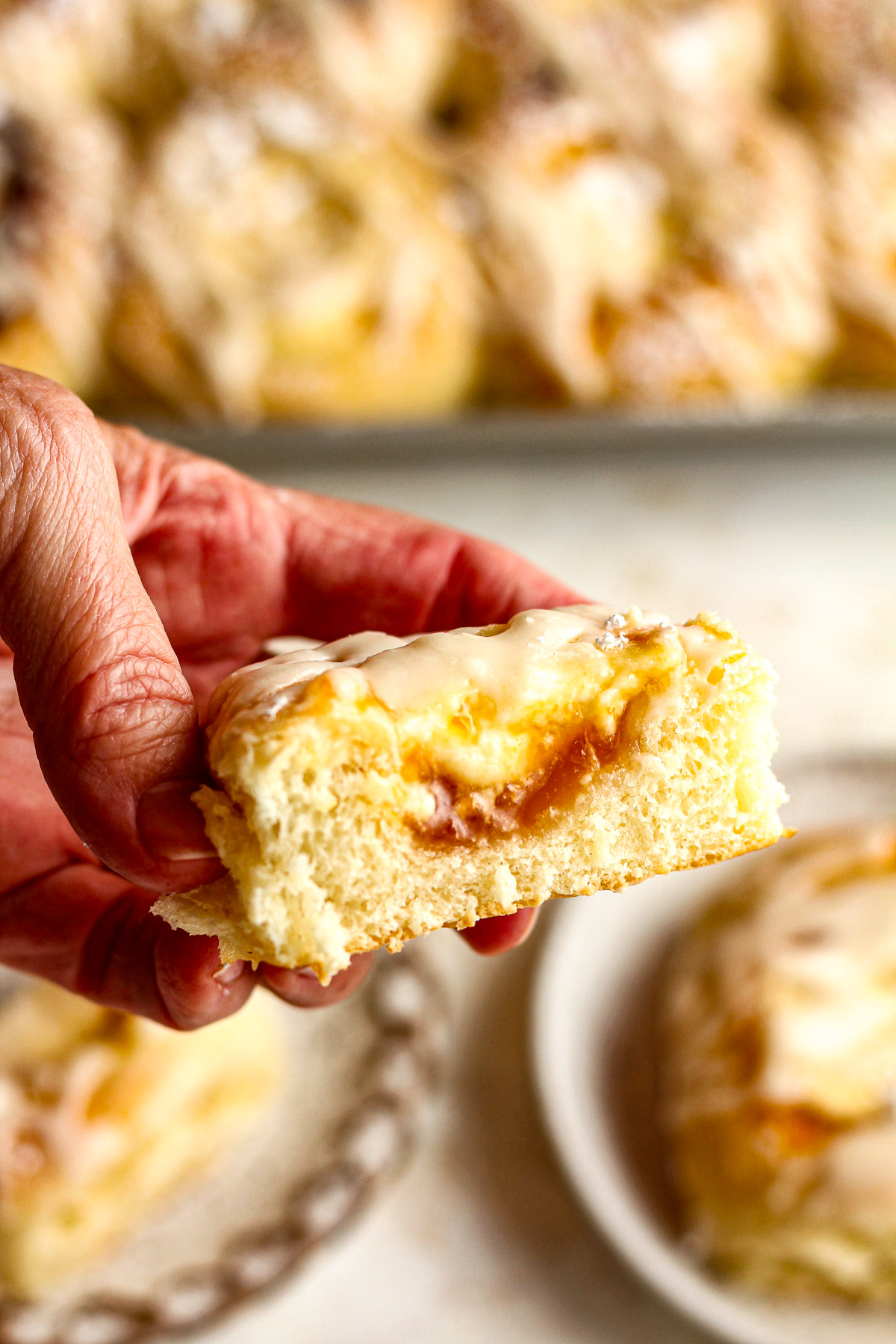 My hand holding half of a kolache showing the fruit and cream cheese filling.
