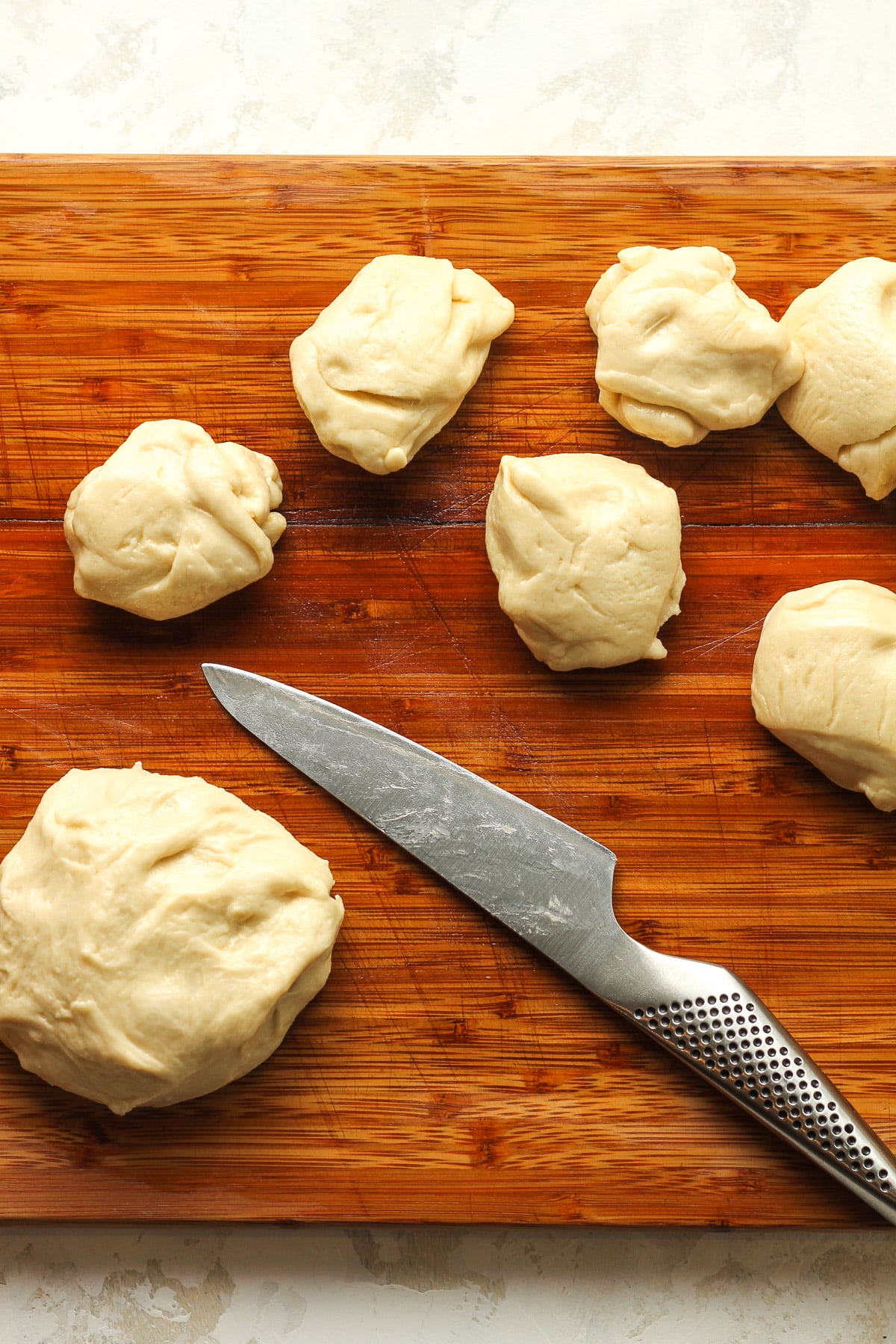 A board of the dough being cut into equal parts.