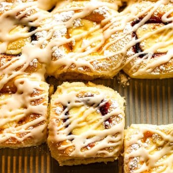 A closeup on a pan of cream cheese kolaches with some of them pulled apart.