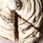 Closeup on the cinnamon roll with one wedge being pulled away.