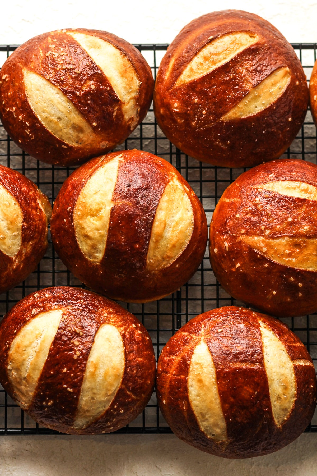Overhead view of some pretzel buns on a wire rack.