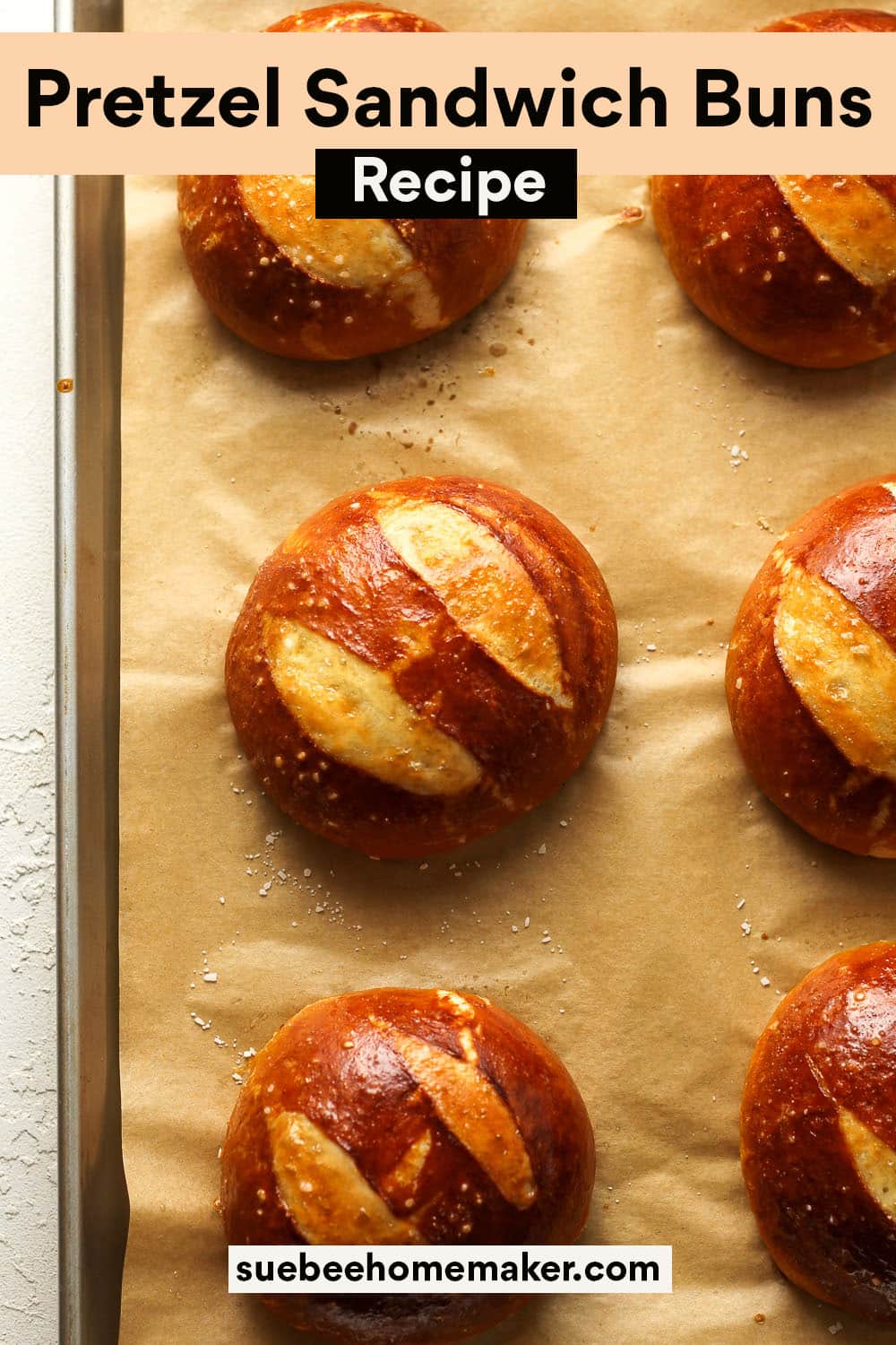 A pan of six baked pretzel sandwich buns.