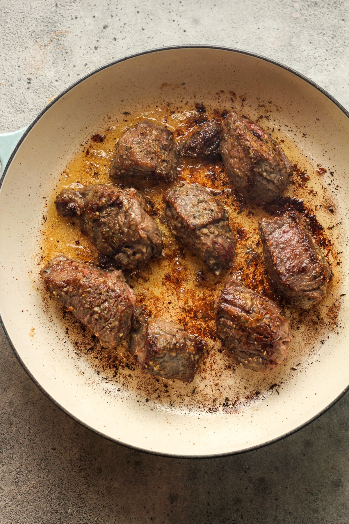 A braiser with seared chunks of beef roast.