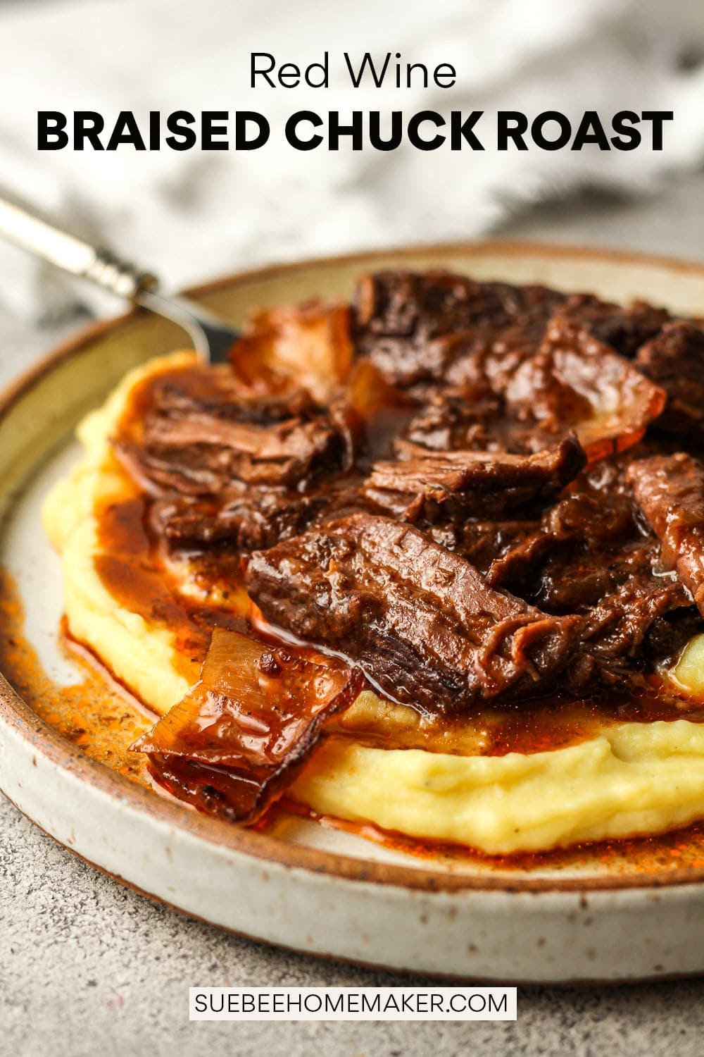 Side view of a plate of red wine braised chuck roast with a fork.