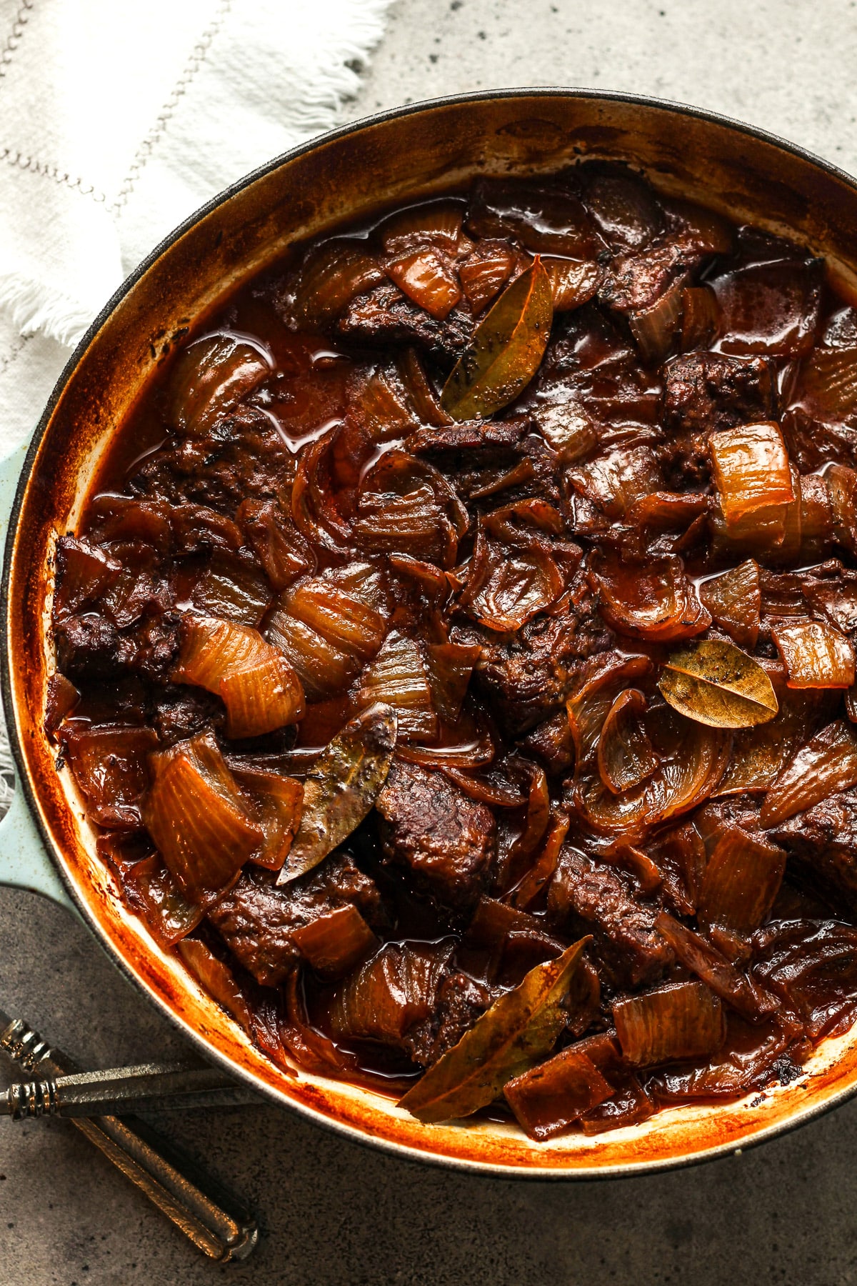 A large round braiser with red wine braised chuck roast with onions.