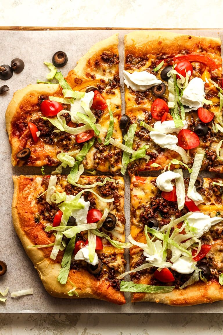 Sliced Godfathers taco pizza with lettuce tomato, sour cream, and olives.