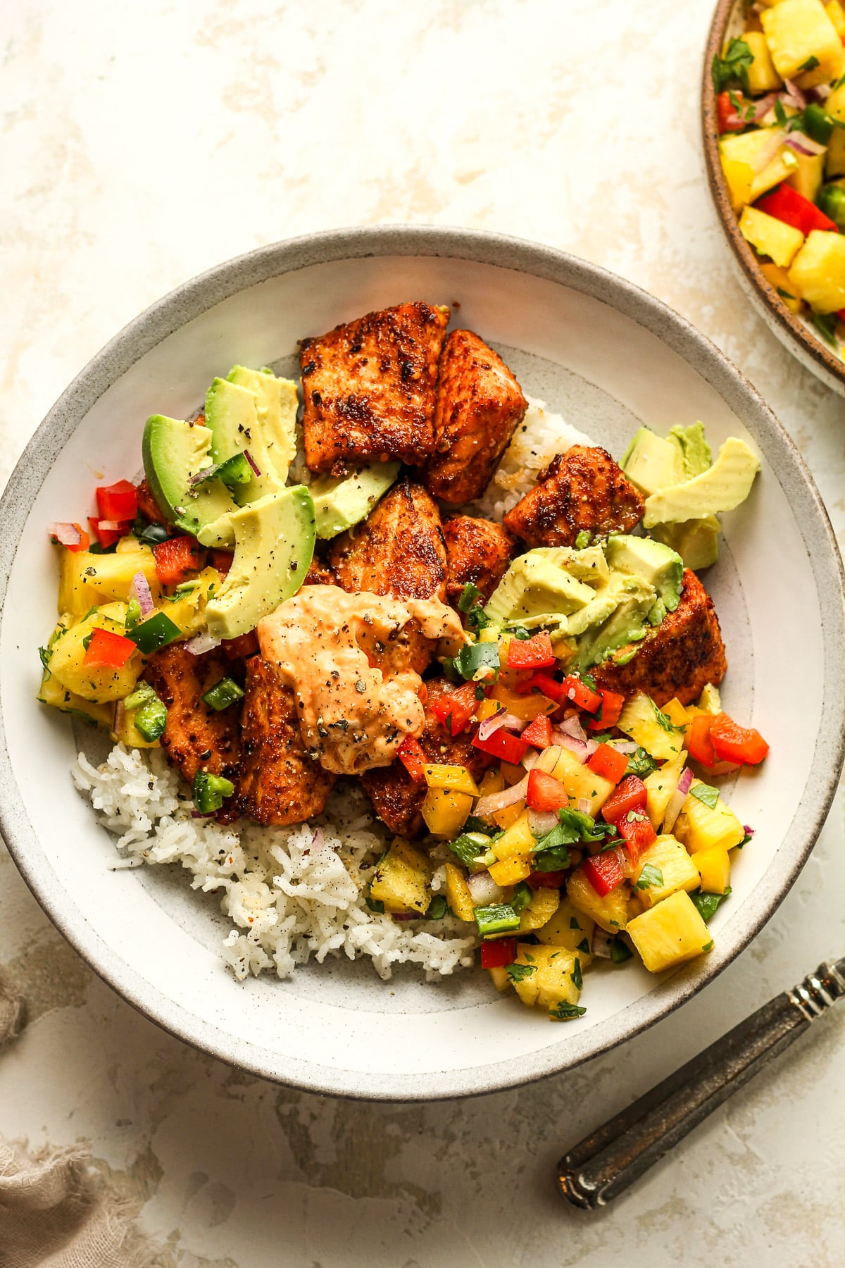 A salmon bowl with white rice and pineapple salsa.