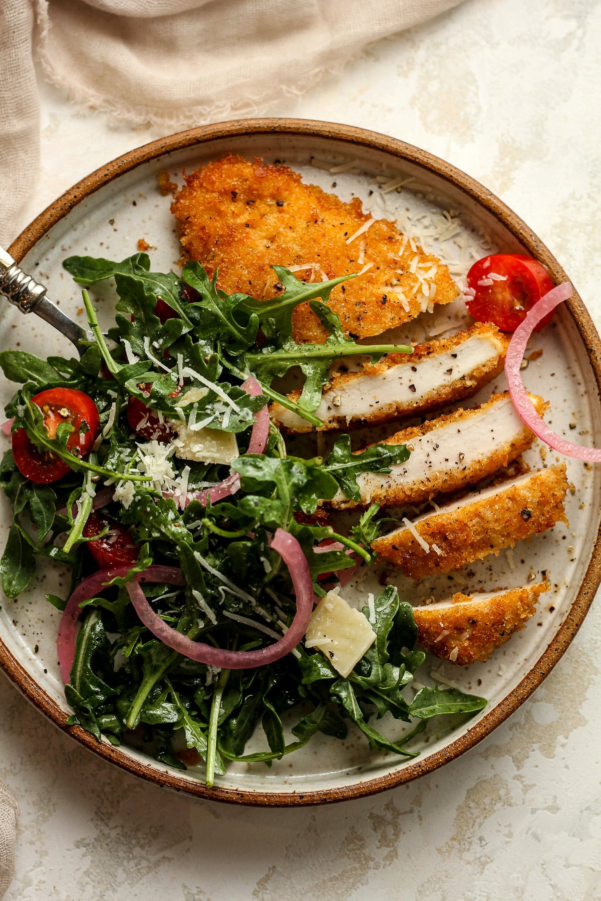 A panko parmesan encrusted chicken cutlet sliced into strips with arugala.