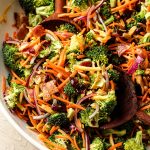 Closeup on our classic broccoli salad with cheese and bacon, showing wooden spoons inside the bowl.