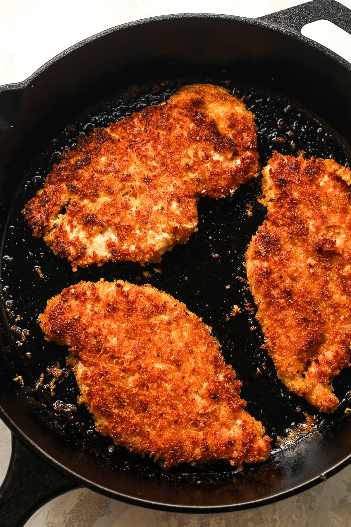 A skillet of the lightly fried panko parmesan encrusted chicken.