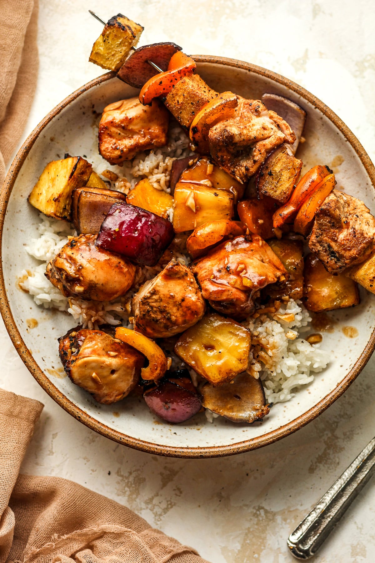 Overhead view of a bowl of the chicken kabobs with one skewer on top too.