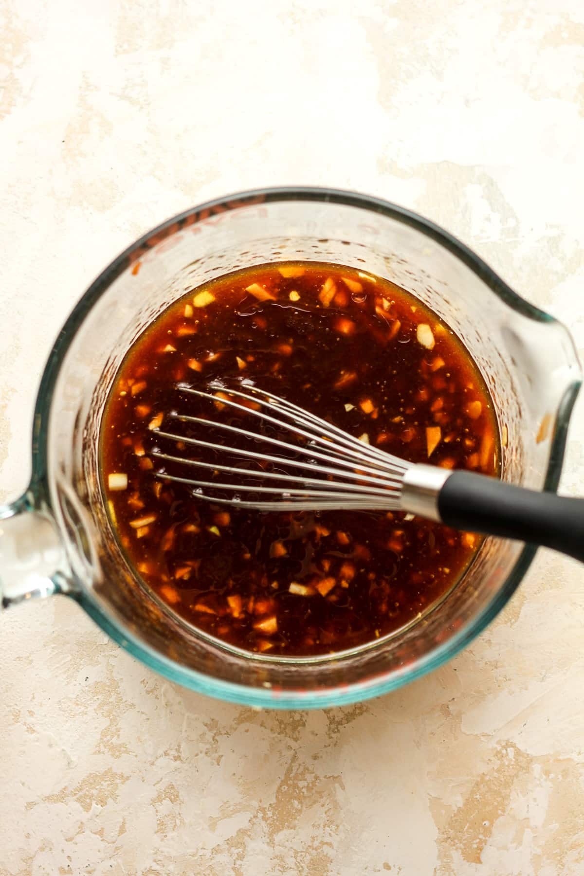 A large measuring cup with the whisked marinade.