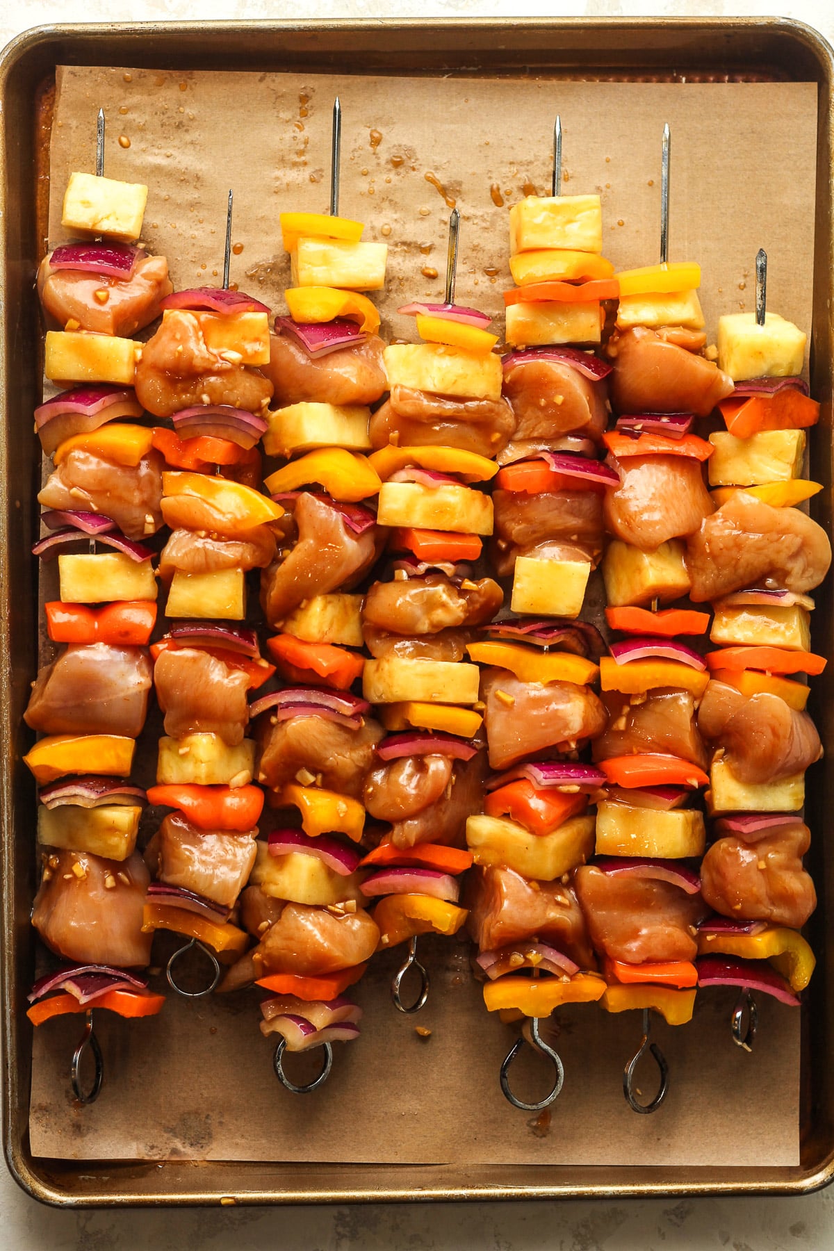 Seven raw kabobs on a pan ready to grill.