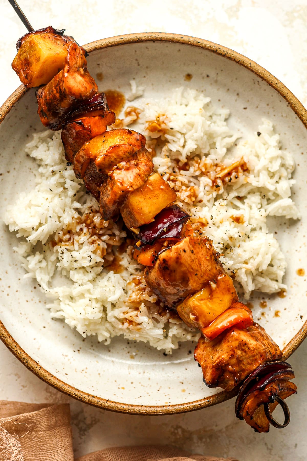 A bowl of rice with one large kabob on top.