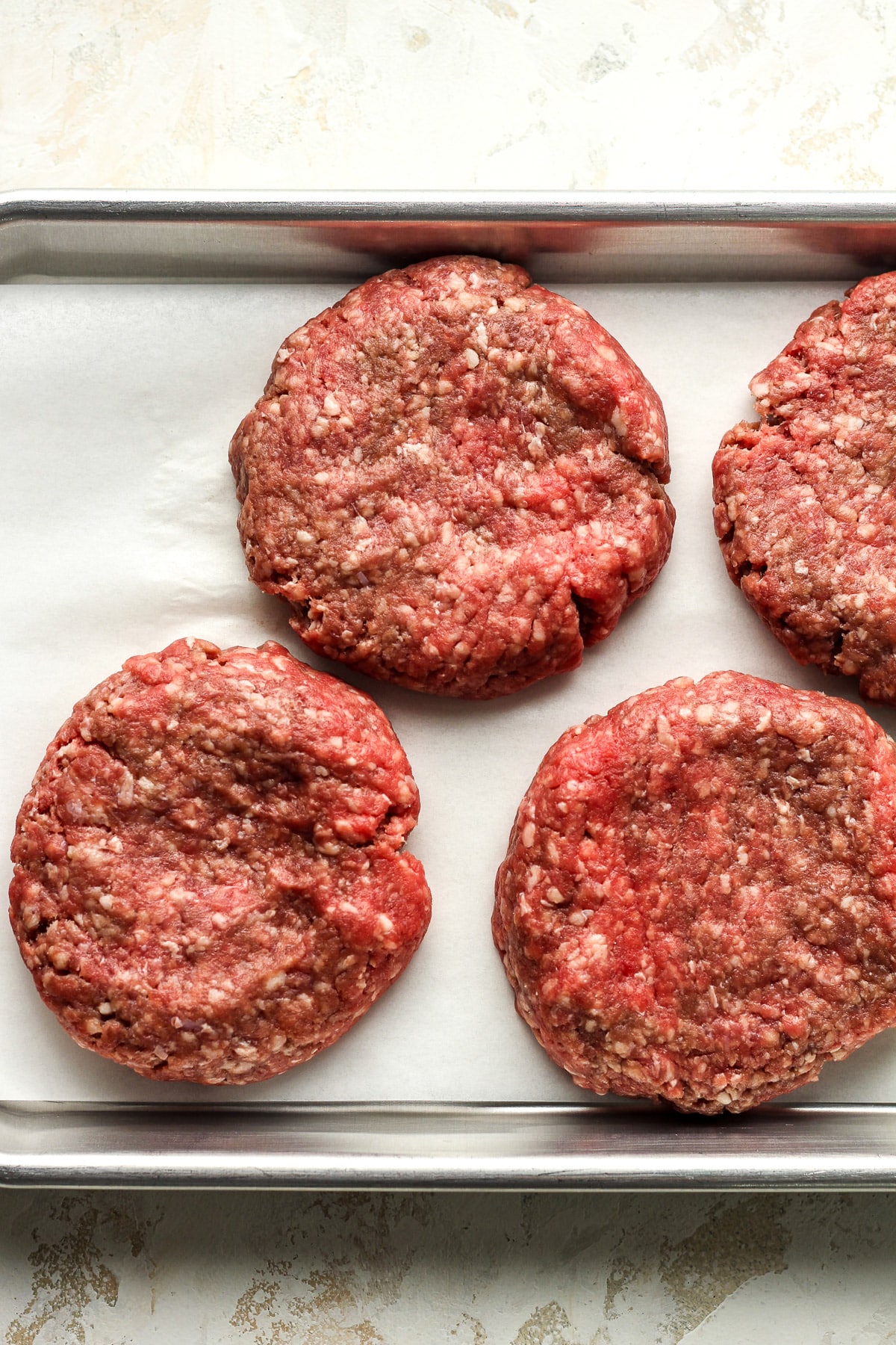 A pan of four beef burger patties.