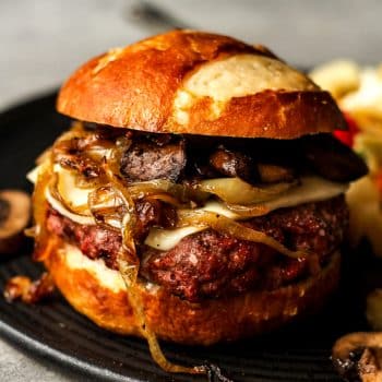 Closeup side view of a mushroom Swiss burger with caramlized onions.