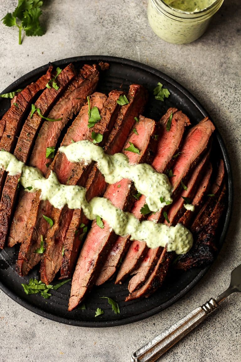 A plate of thinly sliced carne asada with cilantro lime crema.