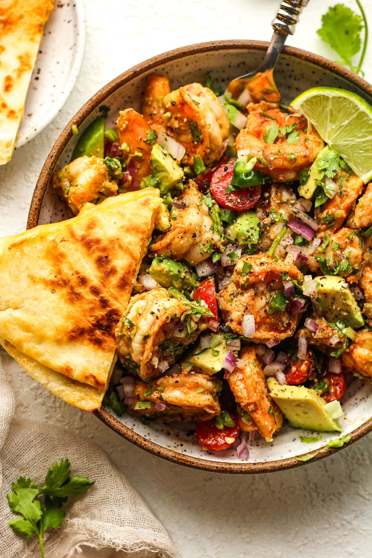 Closeup on a serving of easy Mexican shrimp salad with a quesadilla wedge.