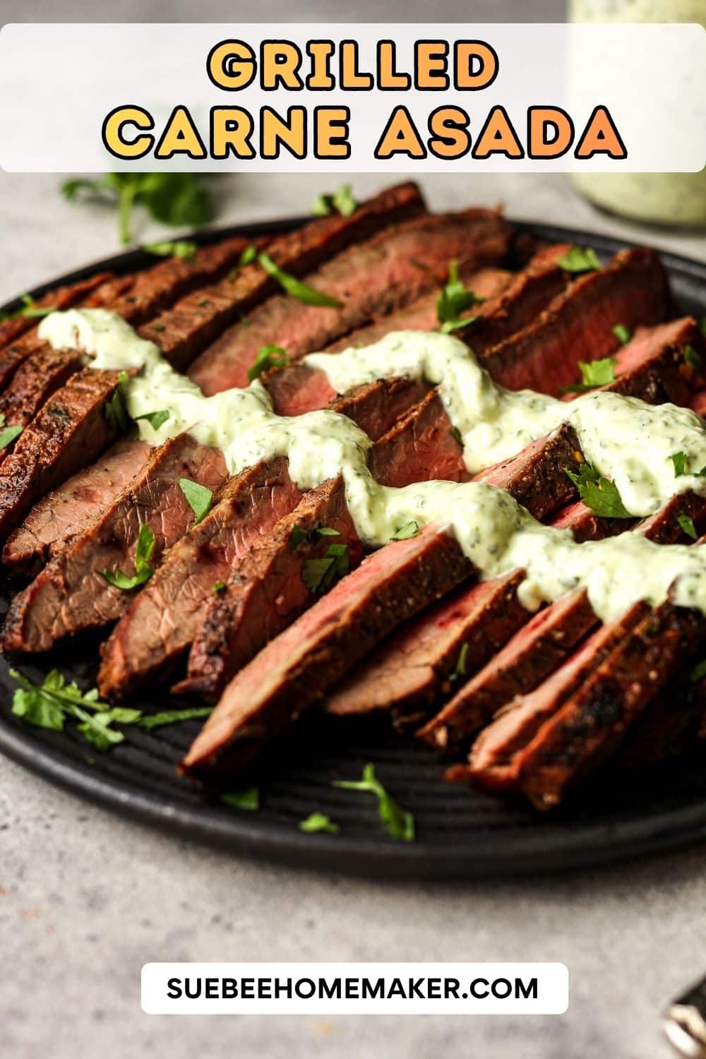 Side view of a black plate with grilled carne asada and a drizzle of cilantro lime crema.