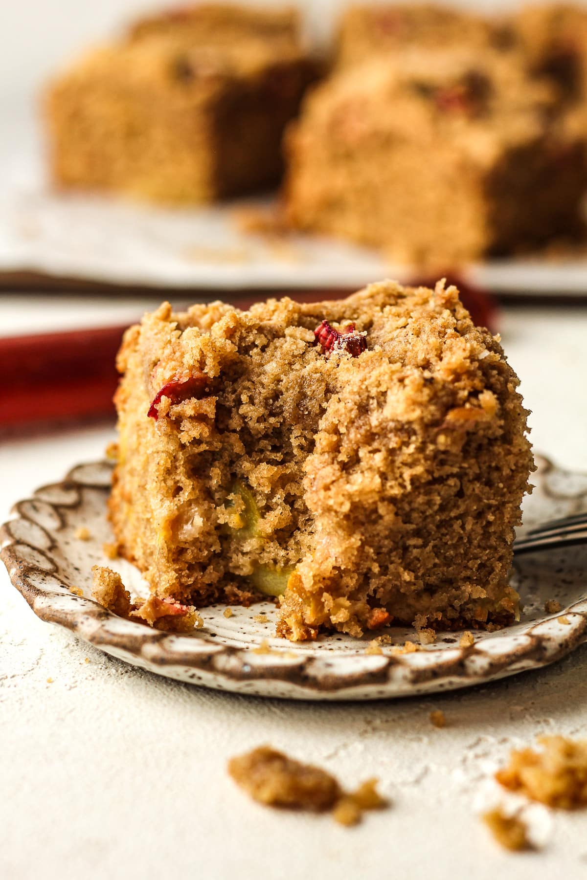 A small plate with a slice of rhubarb cake with a bite removed.