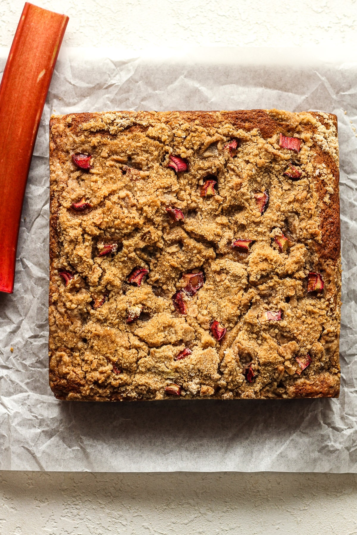 A square rhubarb cake with tiny pieces of rhubarb on top.