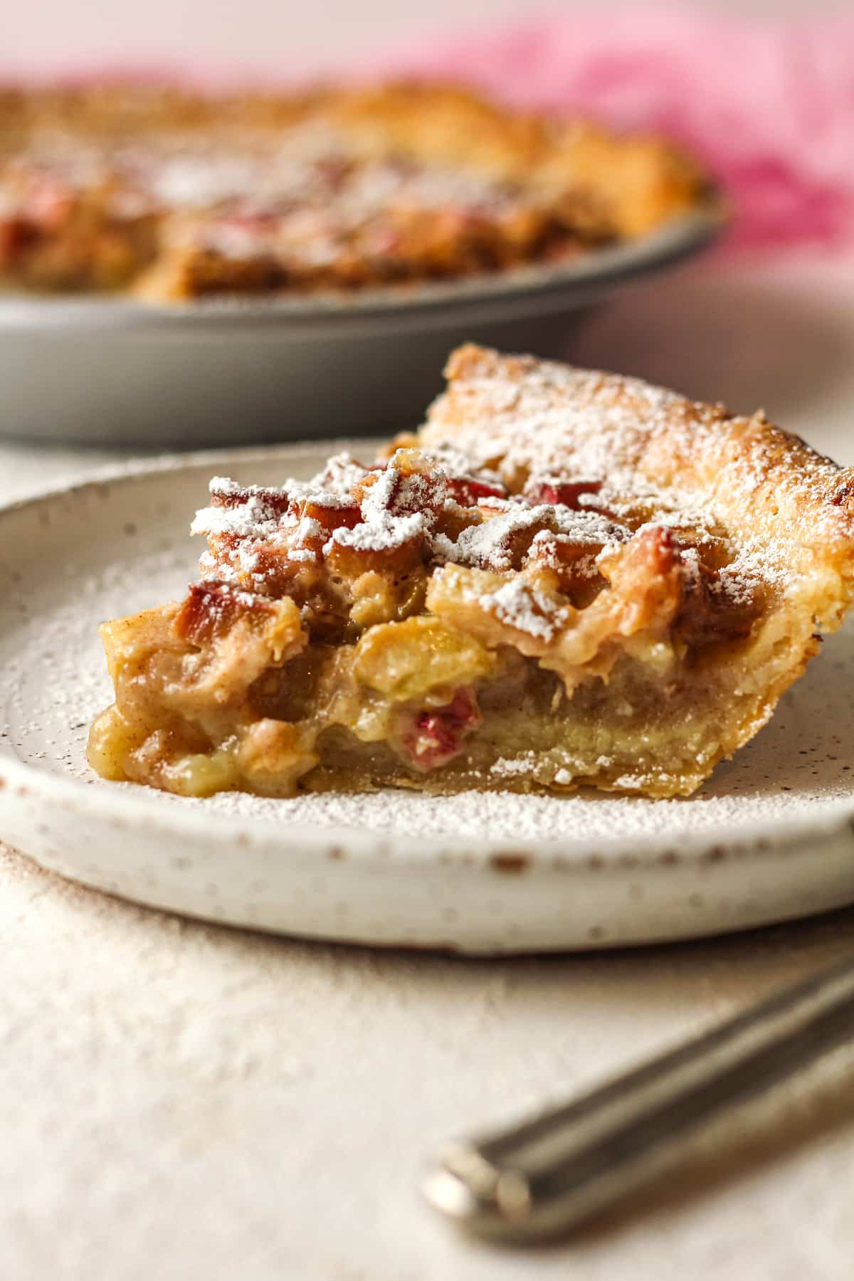 Side view of a small plate with a slice of rhubarb custard pie.