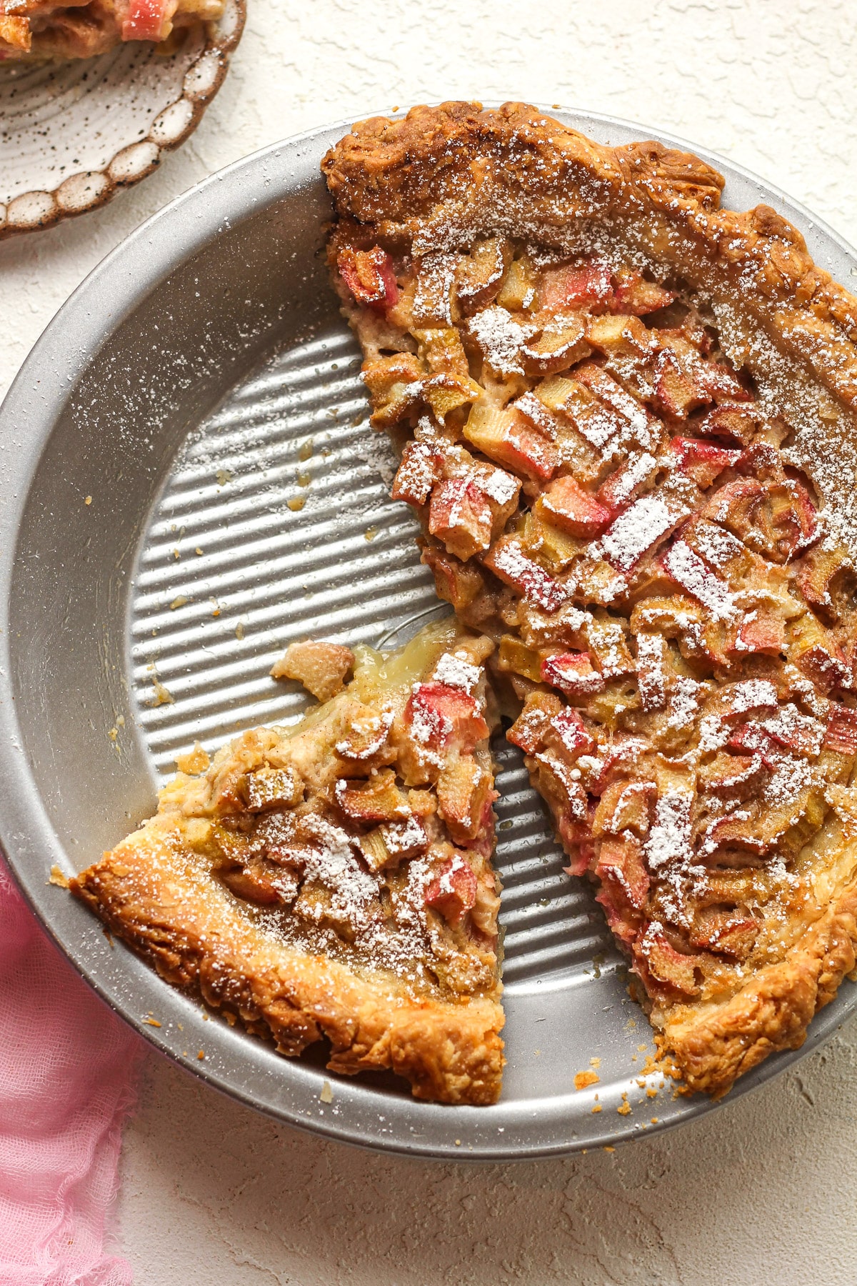 A pie plate of rhubarb custard pie with some pie removed.
