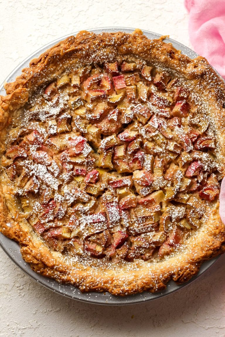 Overhead view of a rhubarb custard pie with a powdered sugar dusting.